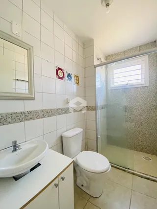 Foto de um banheiro com revestimento cerâmico e louças sanitárias brancas.