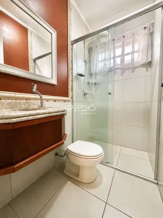 Foto de um banheiro com revestimento cerâmico e box de vidro.