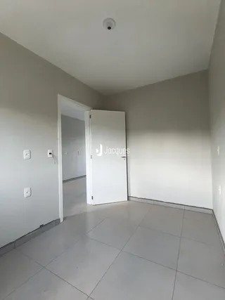 Hall de entrada com piso de cerâmica claro e porta branca.