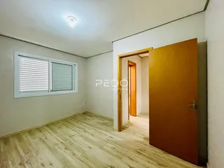 Ambiente interno de uma sala com piso de madeira clara e janela.