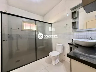 Banheiro com box de vidro e bancada escura em um imóvel.
