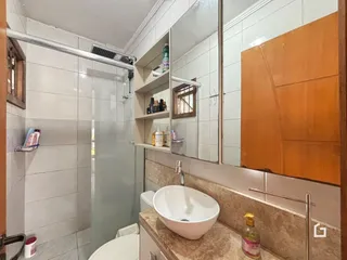Foto interna de um banheiro com revestimento cerâmico e bancada de pia.