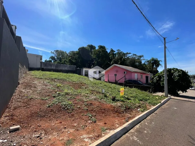 Vista externa de um terreno com vegetação e construções ao fundo.