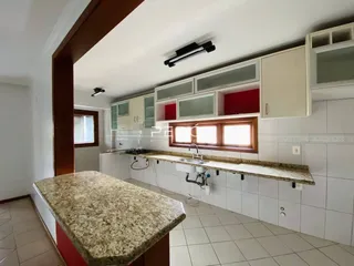 Vista da cozinha com armários brancos e bancada de granito.