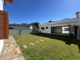 Fachada de uma residência com jardim e pátio gramado.