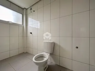 Banheiro com piso e paredes brancas em cerâmica.