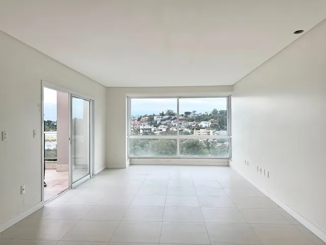 Uma sala ampla com piso de porcelanato e grande janela com vista para a paisagem.