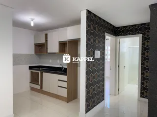 Cozinha com armários brancos e bancada escura em um imóvel.