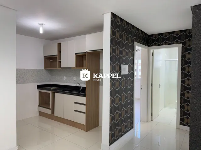 Cozinha com armários brancos e bancada escura em um imóvel.