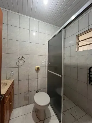 Banheiro com revestimento de azulejos brancos e box de vidro.