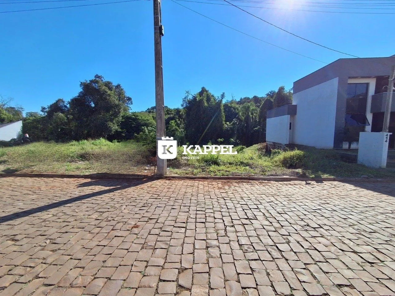 Fachada de uma residência branca em Lajeado, Brasil, com área externa pavimentada.