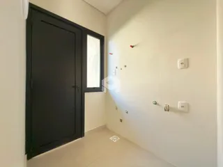 Hall de entrada com porta escura e janela na parede.