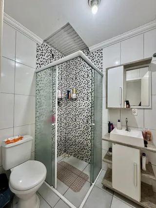 Foto de um banheiro com revestimento cerâmico e box de vidro.