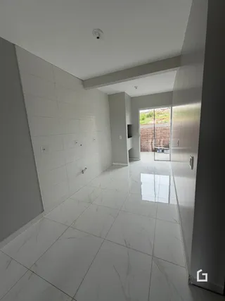 Corredor interno com piso de cerâmica e paredes brancas.
