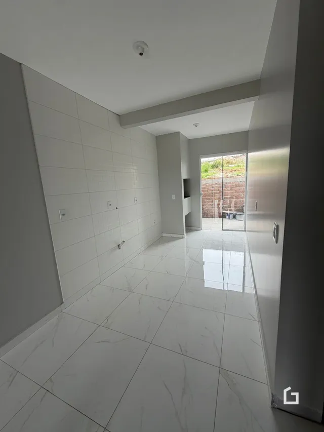 Corredor interno com piso de cerâmica e paredes brancas.