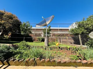 Fachada de uma propriedade com jardim e cerca.