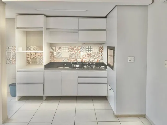 Cozinha moderna com armários brancos e revestimento de azulejos.