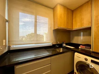 Cozinha com armários de madeira e bancada escura.