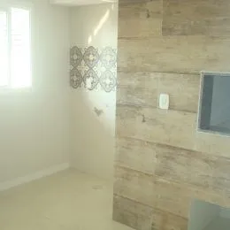 Foto interna de uma sala com parede texturizada e janela.