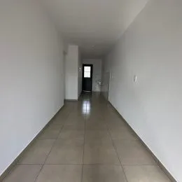 Corredor interno com paredes brancas e piso de cerâmica.