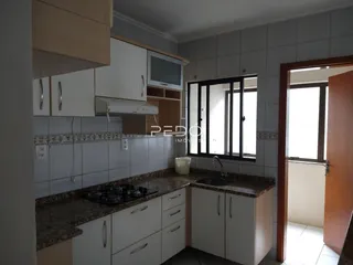 Foto de uma cozinha com armários brancos e bancadas escuras.