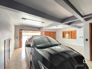 Interior de uma área de passagem com paredes brancas e vigas cinzas.
