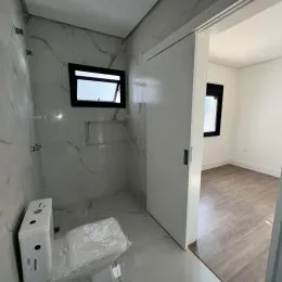 Foto interna de um banheiro com paredes claras e revestimento de azulejo.