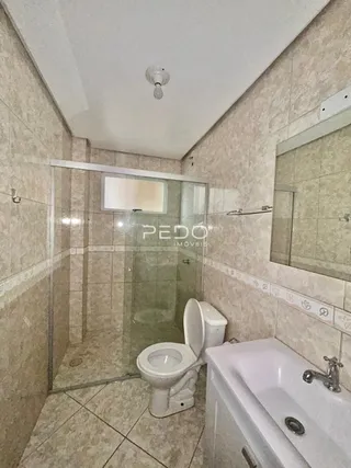 Foto de um banheiro com revestimento cerâmico e box de vidro.