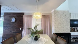 A sala de jantar apresenta paredes de madeira e cortinas claras.