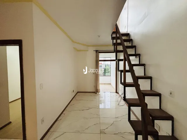 Corredor interno de uma residência com piso de mármore e escadaria de madeira escura.