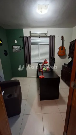 Sala de estar com paredes verdes e piso de cerâmica clara.