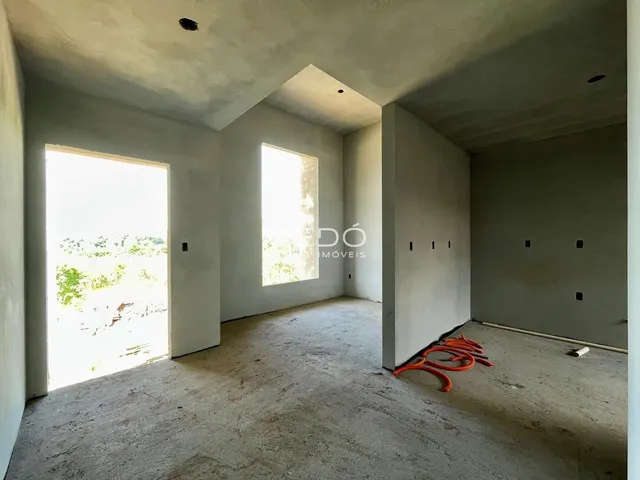 Interior de um espaço com paredes brancas e piso de concreto cru.