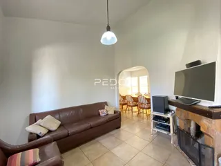 Uma sala de estar com sofá de couro marrom e piso de cerâmica.