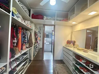 Quarto com estantes e roupas penduradas em um ambiente interno.