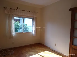 Interior de uma sala com piso de madeira e janela.