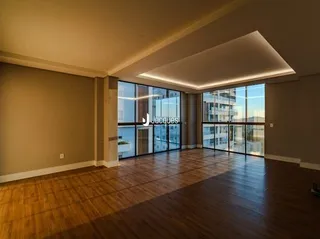 Sala de estar com piso de madeira e grandes janelas.