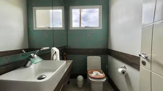 Banheiro com bancada de madeira e vaso sanitário branco.