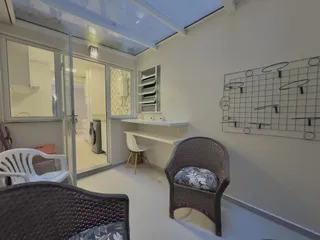 Sala de estar clara com móveis de vime e paredes brancas.