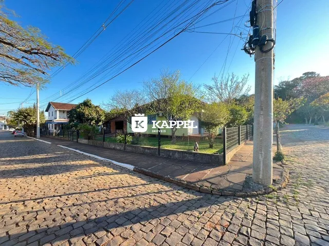 Vista externa de uma rua pavimentada com uma cerca e uma residência ao fundo.