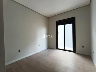 Vista interna de um cômodo com paredes brancas e piso de madeira.