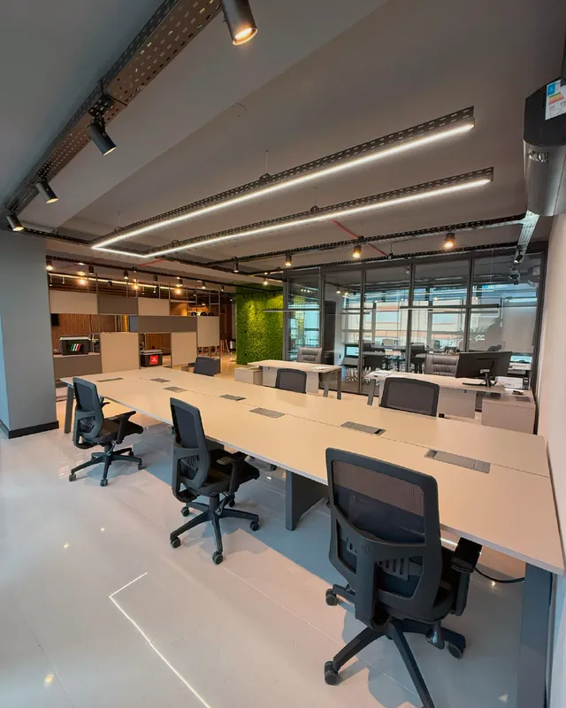 Ambiente de escritório moderno com mesa de reunião e cadeiras em um espaço amplo.