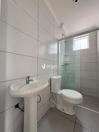 Foto interna de um banheiro com azulejos brancos e box de vidro.