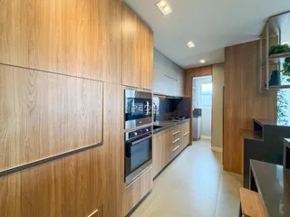 Vista da cozinha moderna com armários de madeira e eletrodomésticos em Lajeado.