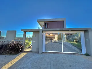 Fachada moderna de uma residência em Lajeado, Brasil, com entrada de vidro e área pavimentada.