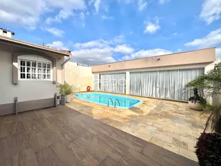 Fachada de casa com piscina e área externa pavimentada.