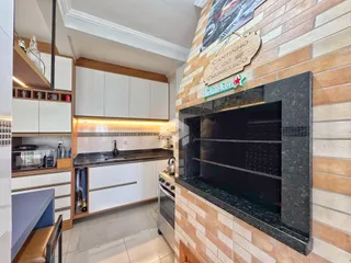 Vista da cozinha com armários brancos e forno de tijolos.