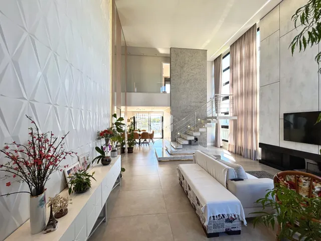 Sala de estar moderna com piso claro e grandes janelas.