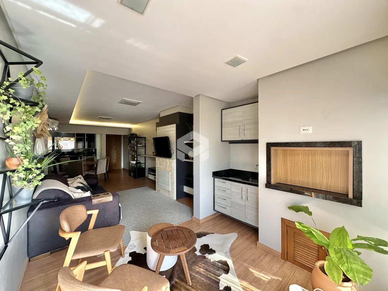 Sala de estar com decoração moderna e piso de madeira clara.