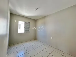 Um corredor interno com piso de cerâmica branca e paredes claras.