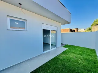 Fachada de uma casa moderna branca com porta de vidro e gramado.